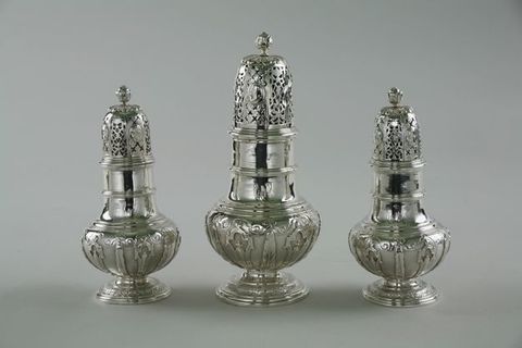 Metalwork. Three different-sized casters would have been used like salt and pepper shakers. Each has an elongated top pierced with x-shaped and lacy designs. They have two-tiered, columnar necks and bulbous bodies over low, flaring feet.